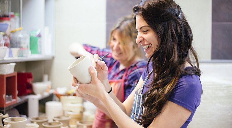 Person painting a cup happily